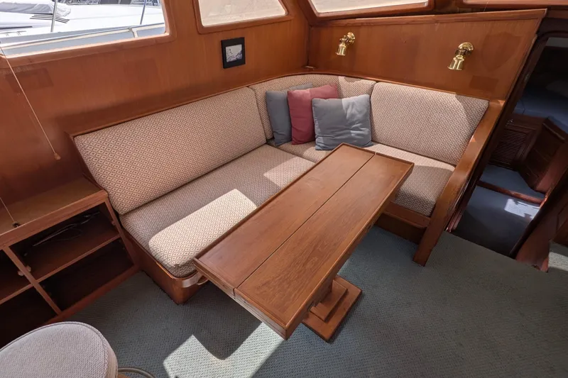 Fisher Folly IV Yacht Photos Pics Cozy interior of 1988 Offshore Yachts 48 Yachtfisher with cushioned seating and wooden table.