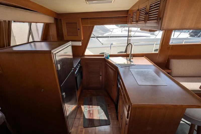 Fisher Folly IV Yacht Photos Pics Interior of 1988 Offshore Yachts 48 Yachtfisher, featuring a compact kitchen with wood cabinetry.