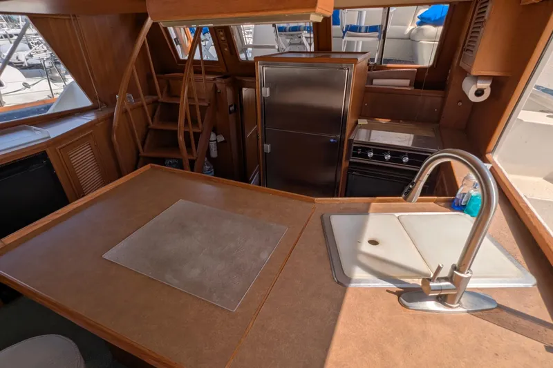 Fisher Folly IV Yacht Photos Pics 1988 Offshore Yachts 48 Yachtfisher interior kitchen with sink, stove, and wooden cabinetry.