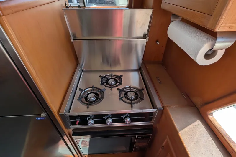 Fisher Folly IV Yacht Photos Pics Compact kitchen with a three-burner stove in a 1988 Offshore Yachts 48 Yachtfisher.