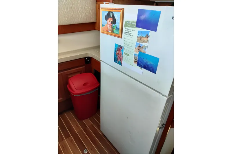  Yacht Photos Pics Refrigerator in 1999 Viking 45 Convertible boat kitchen with photos and red trash bin.