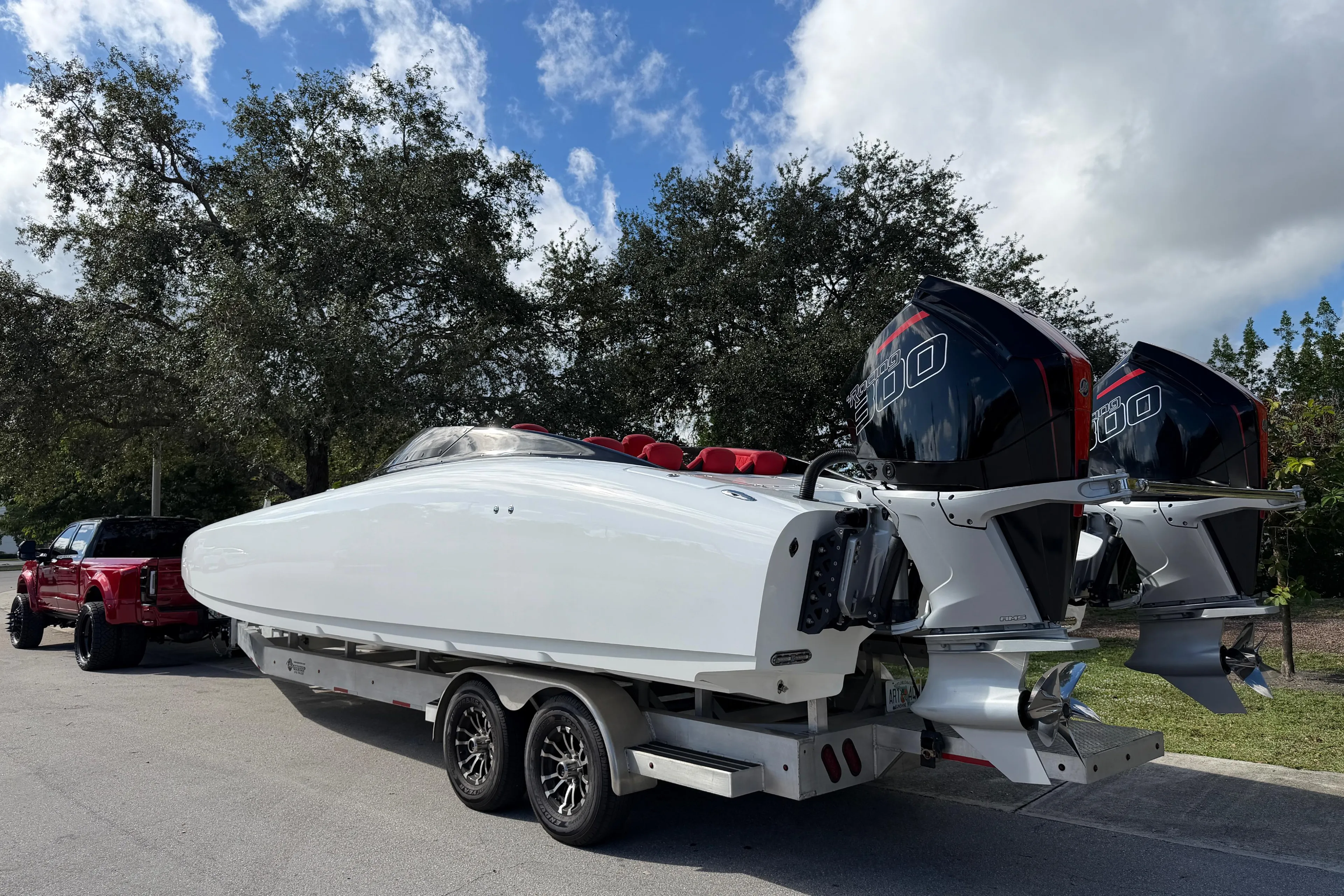 2022 Doug Wright 320 powerboat on trailer with twin engines, parked near trees.