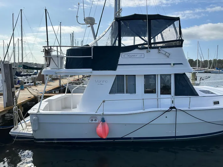 Chapter 2 Yacht Photos Pics 1998 Mainship 350 Trawler docked at marina, featuring upper deck and cabin.