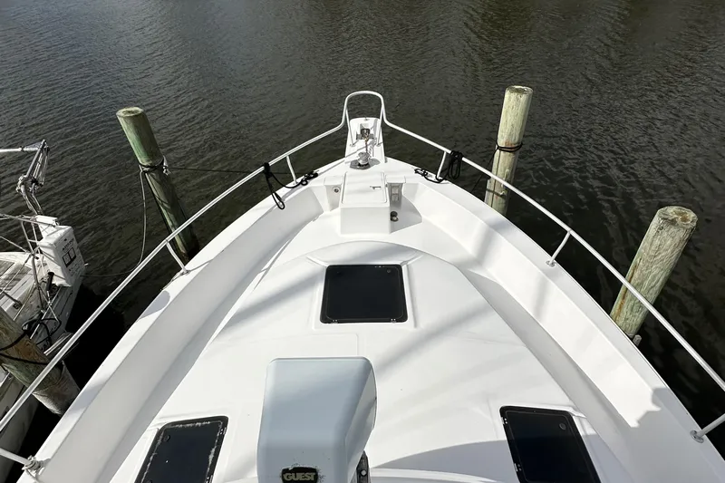 Chapter 2 Yacht Photos Pics 1998 Mainship 350 Trawler bow view, docked with calm water and pilings.