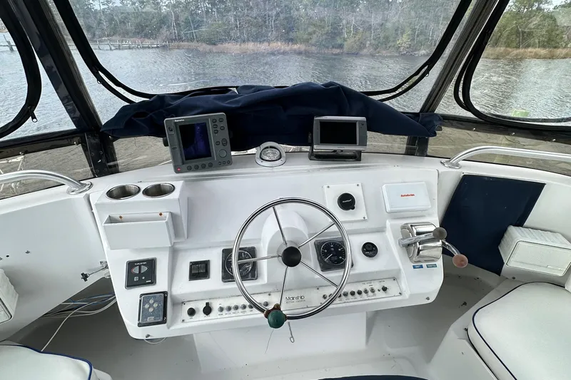 Chapter 2 Yacht Photos Pics 1998 Mainship 350 Trawler helm with steering wheel, navigation instruments, and water view.