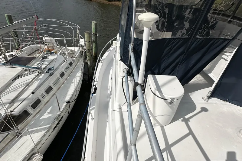 Chapter 2 Yacht Photos Pics 1998 Mainship 350 Trawler docked beside another boat, showcasing deck and railing.