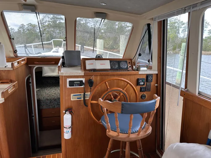 Chapter 2 Yacht Photos Pics 1998 Mainship 350 Trawler helm with wooden wheel, navigation instruments, and cozy cabin interior.
