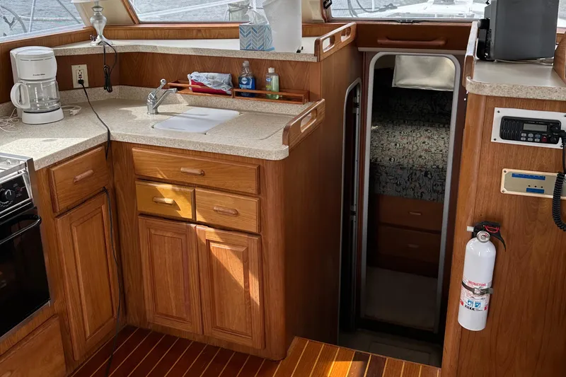 Chapter 2 Yacht Photos Pics 1998 Mainship 350 Trawler interior with wooden cabinetry, kitchenette, and cozy sleeping area.