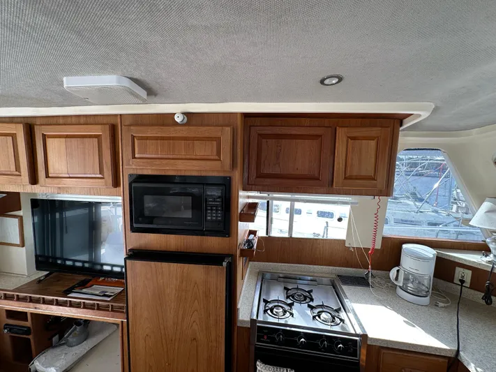 Chapter 2 Yacht Photos Pics 1998 Mainship 350 Trawler kitchen with wood cabinets, stove, microwave, and countertop appliances.