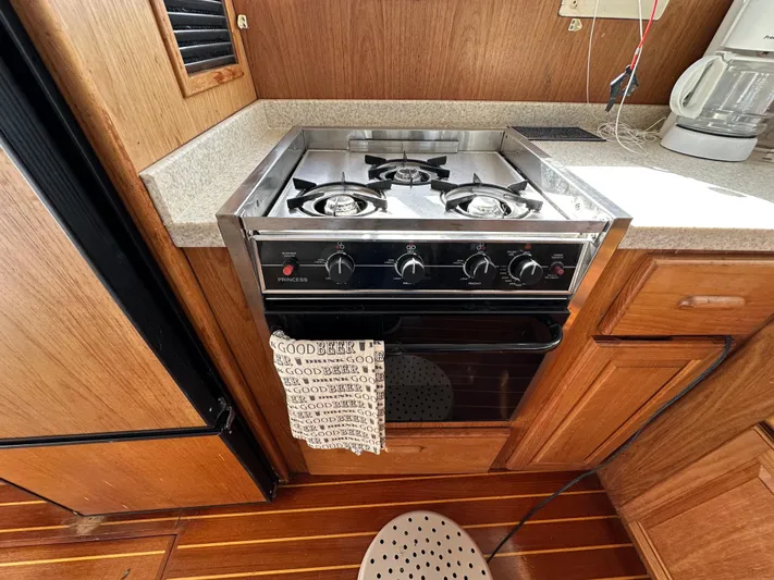 Chapter 2 Yacht Photos Pics 1998 Mainship 350 Trawler kitchen with stove, wooden cabinets, and countertop appliances.
