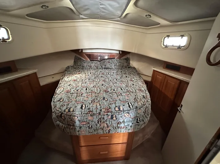 Chapter 2 Yacht Photos Pics 1998 Mainship 350 Trawler cabin with cozy bed, wooden cabinets, and natural light.