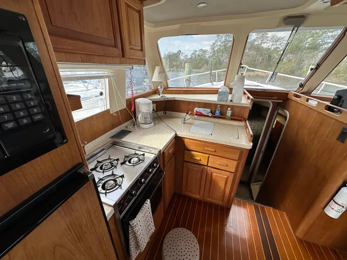 Chapter 2 Yacht Photos Pics 1998 Mainship 350 Trawler kitchen with stove, wooden cabinets, and countertop.