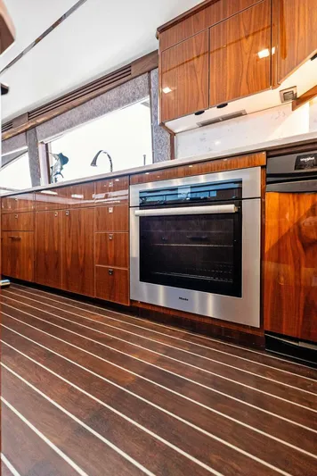 Rachel Anne Yacht Photos Pics Luxurious kitchen interior of 2022 Viking 80 yacht with modern appliances and wood cabinetry.