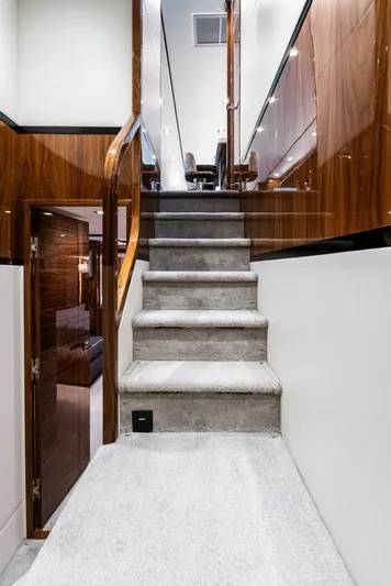 Rachel Anne Yacht Photos Pics Interior staircase of a 2022 Viking 80 yacht with modern wood paneling.