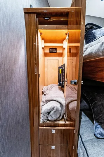 Rachel Anne Yacht Photos Pics Luxurious wooden cabinet in 2022 Viking 80 yacht, featuring neatly folded towels and ambient lighting.