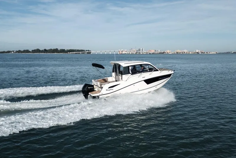  Yacht Photos Pics 2026 Trophy T25EX Explorer OB boat cruising on open water, cityscape in background.