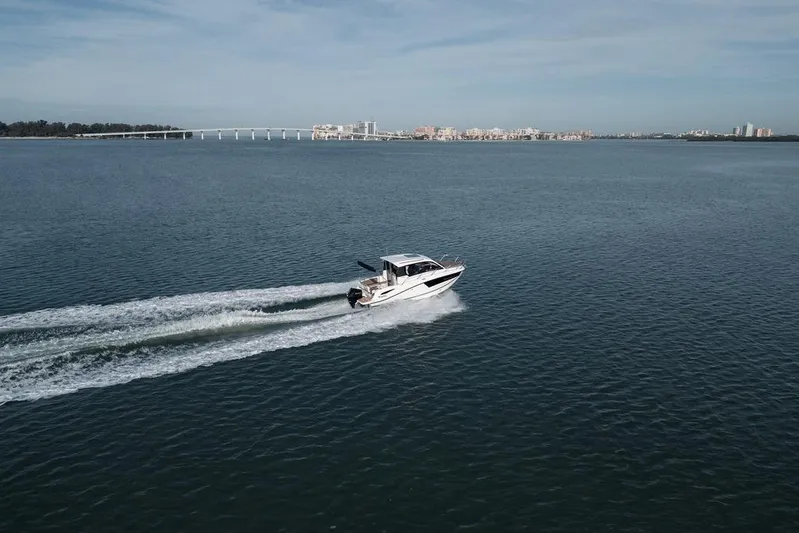  Yacht Photos Pics 2026 Trophy T25EX EXPLORER OB cruising on open water with cityscape in background.