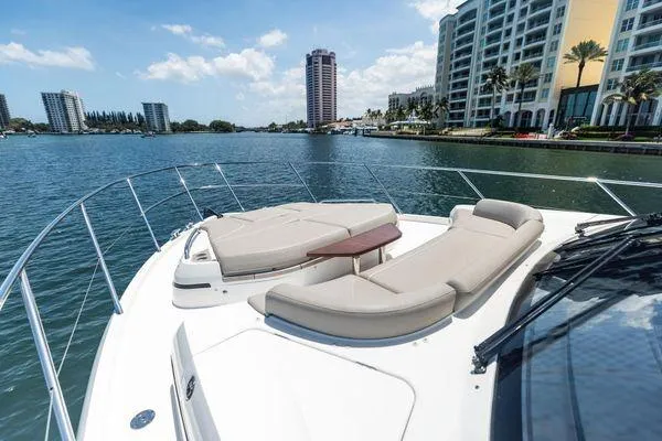 Endless Summer Yacht Photos Pics Luxurious 2020 Princess V55 yacht with sun loungers, cruising near waterfront buildings.