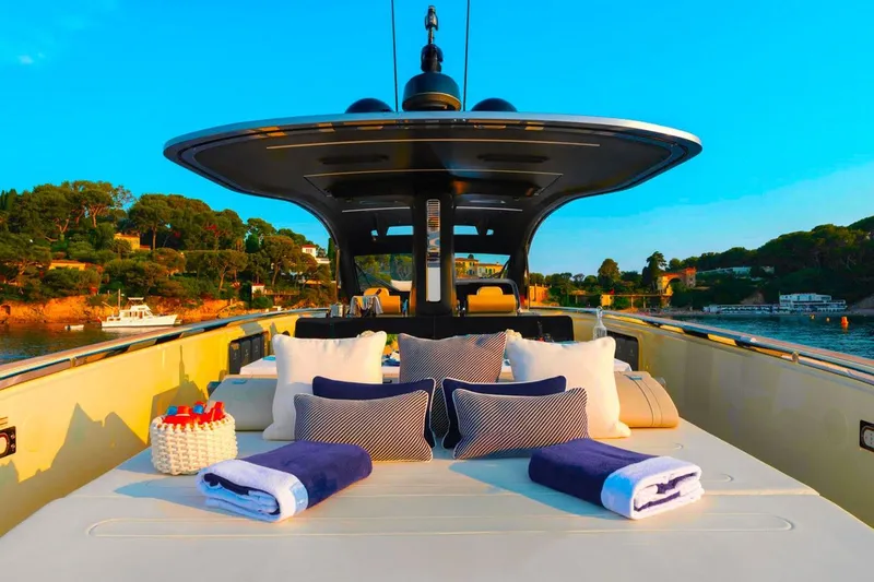  Yacht Photos Pics Luxurious 2023 Invictus TT460 yacht deck with cushions and towels, set against a scenic coastal backdrop.
