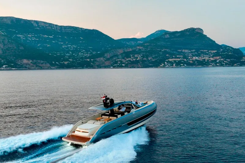  Yacht Photos Pics 2023 Invictus TT460 yacht cruising on serene waters with mountainous backdrop.