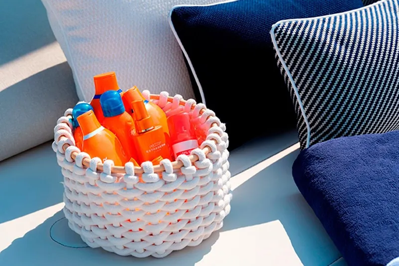  Yacht Photos Pics Basket of sunscreen bottles on Invictus TT460 yacht, 2023, with blue and white cushions.