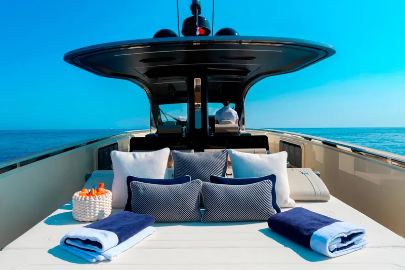  Yacht Photos Pics Luxurious 2023 Invictus TT460 yacht deck with cushions and towels, set against a clear blue sea.