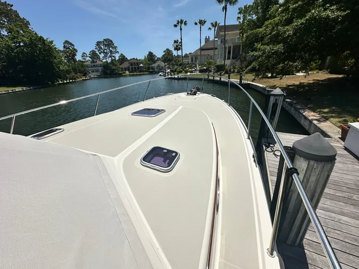  Yacht Photos Pics 2022 Back Cove 372 yacht docked by a scenic waterfront with lush greenery.