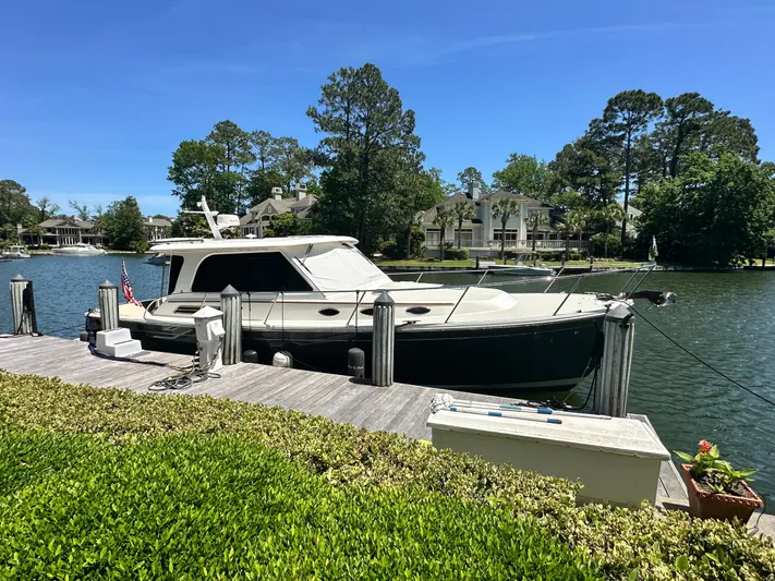  Yacht Photos Pics 2022 Back Cove 372 yacht docked by a scenic waterfront with lush greenery.