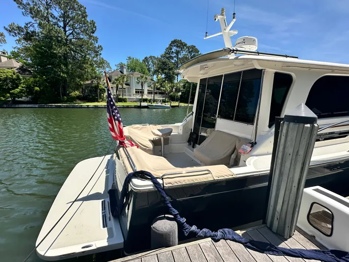  Yacht Photos Pics 2022 Back Cove 372 yacht docked by a serene waterfront with lush greenery.