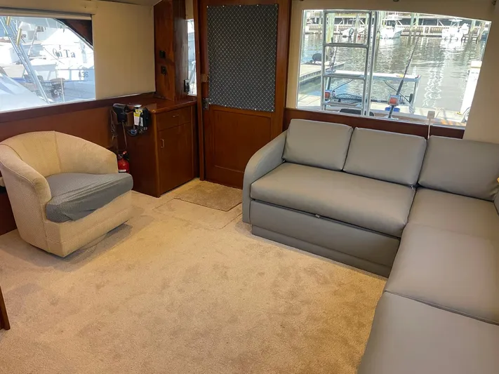 Occtane Yacht Photos Pics Interior of 1990 Ocean Yachts 44 Super Sport with gray sofa, beige chair, and marina view.