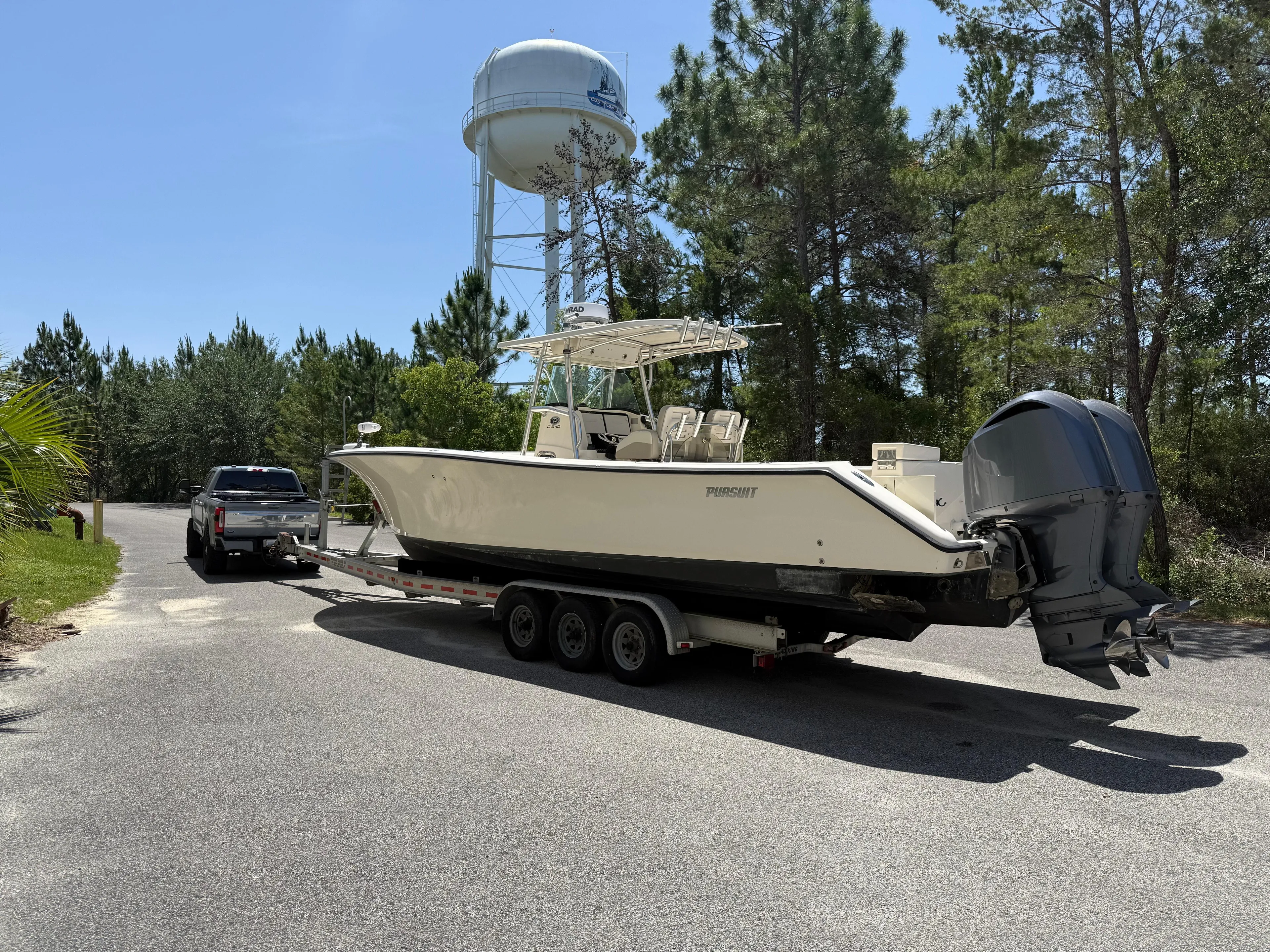  Yacht Photos Pics 2009 Pursuit 3400 Offshore boat on trailer, parked near water tower, surrounded by trees.