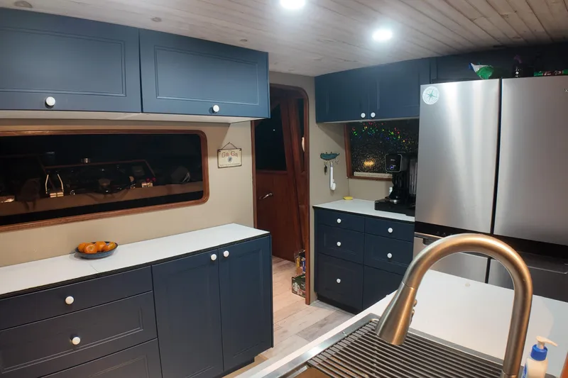  Yacht Photos Pics Modern kitchen interior of 1987 Viking Gulfstar yacht with blue cabinets and stainless steel appliances.