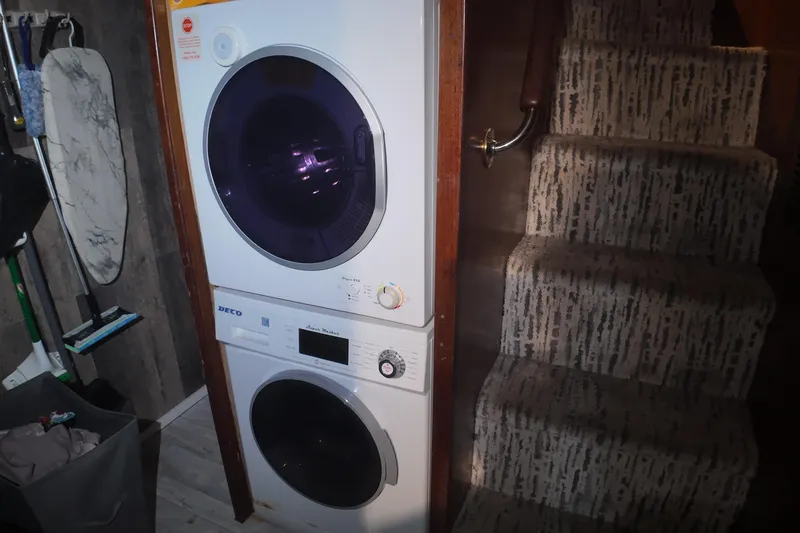  Yacht Photos Pics Stacked washer and dryer beside carpeted stairs in a compact laundry area.