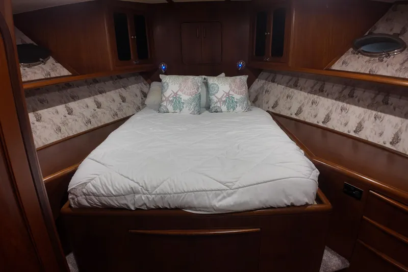 Yacht Photos Pics Cozy bedroom in 1987 Viking Gulfstar yacht with wood paneling and nautical-themed pillows.