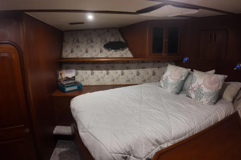  Yacht Photos Pics Cozy bedroom interior of 1987 Viking Gulfstar yacht with wood paneling and decorative pillows.