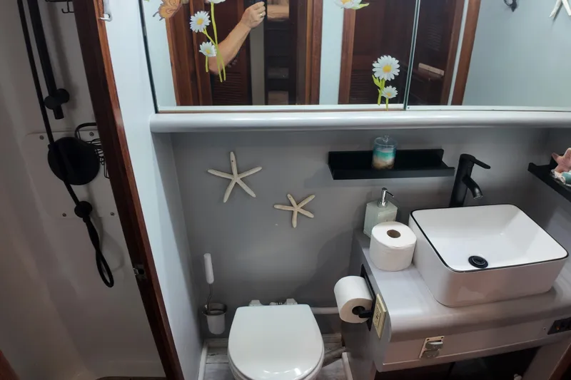  Yacht Photos Pics 1987 Viking Gulfstar bathroom with modern sink, starfish decor, and floral mirror accents.