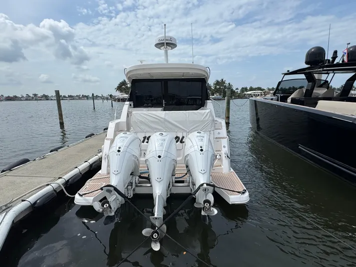 19th Hole Yacht Photos Pics 2024 Regal 38 XO boat docked with triple outboard engines, under a partly cloudy sky.