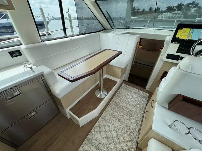 19th Hole Yacht Photos Pics 2024 Regal 38 XO yacht interior with white seating, wooden table, and navigation equipment.
