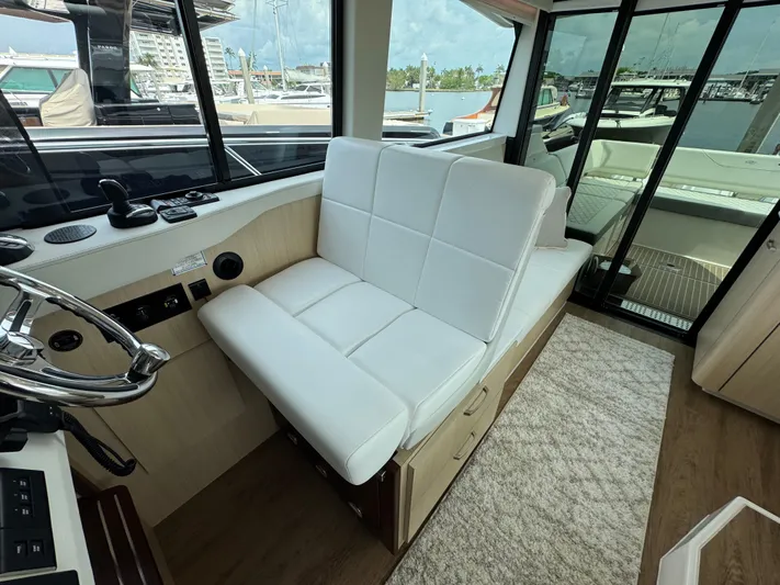 19th Hole Yacht Photos Pics 2024 Regal 38 XO yacht interior with white seating and helm, docked at marina.