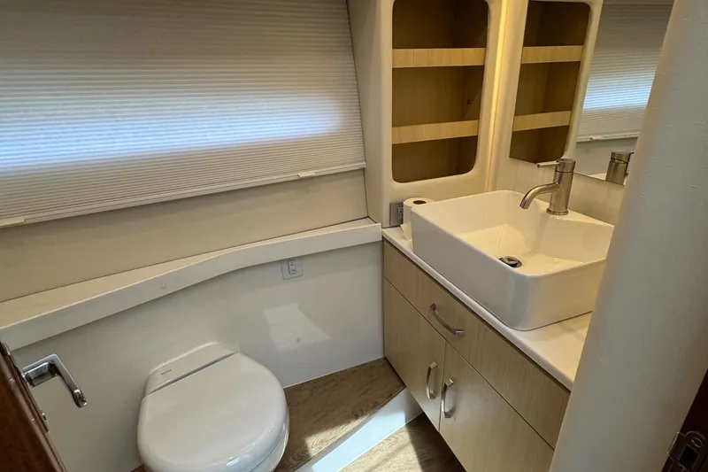 19th Hole Yacht Photos Pics 2024 Regal 38 XO yacht bathroom with modern sink, toilet, and wooden cabinetry.
