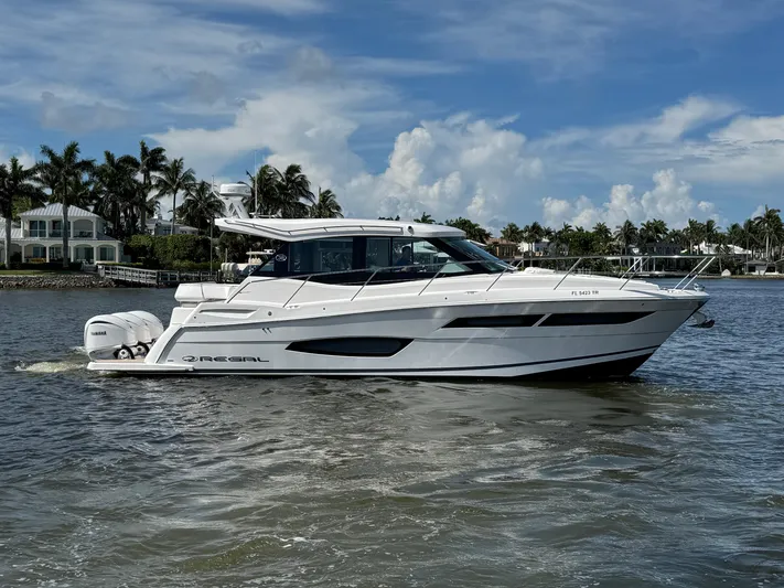 19th Hole Yacht Photos Pics 2024 Regal 38 XO yacht cruising on a sunny day with palm trees in the background.