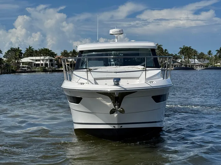 19th Hole Yacht Photos Pics 2024 Regal 38 XO yacht cruising on a sunny day, surrounded by palm trees and waterfront homes.