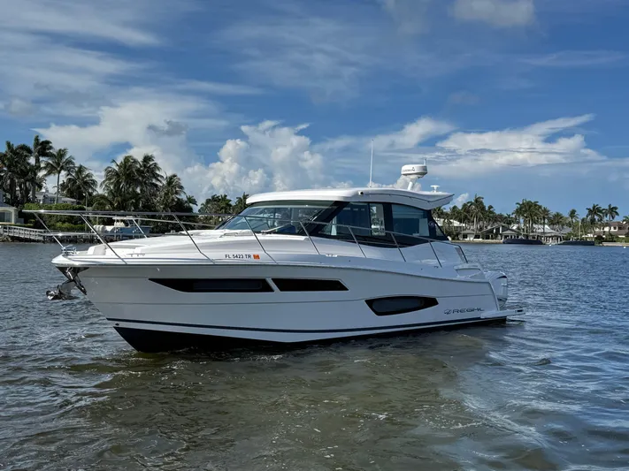 19th Hole Yacht Photos Pics 2024 Regal 38 XO yacht cruising on a sunny day with palm trees in the background.