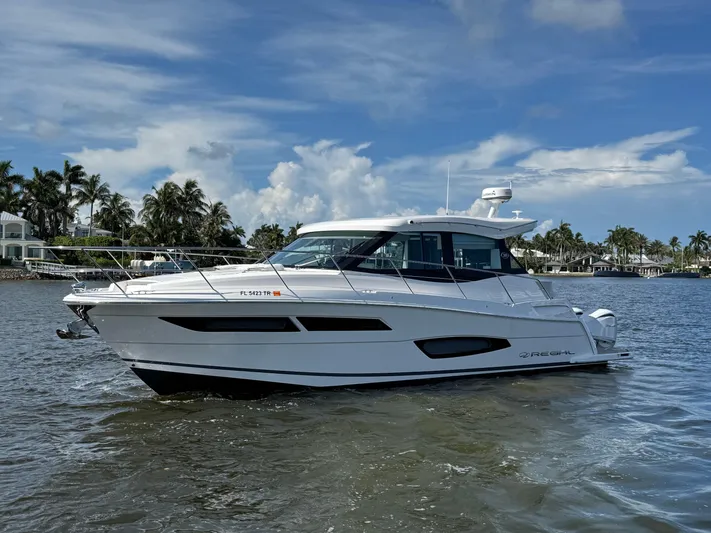 19th Hole Yacht Photos Pics 2024 Regal 38 XO yacht cruising on a sunny day with palm trees in the background.