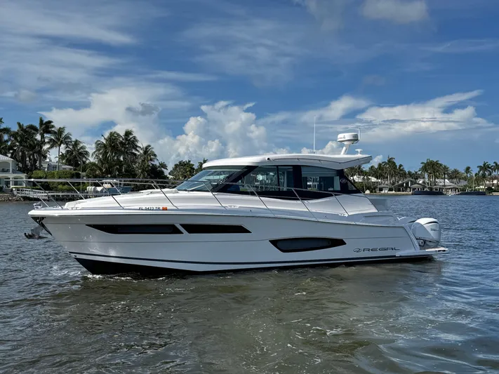 19th Hole Yacht Photos Pics 2024 Regal 38 XO yacht cruising on a sunny day with palm trees in the background.