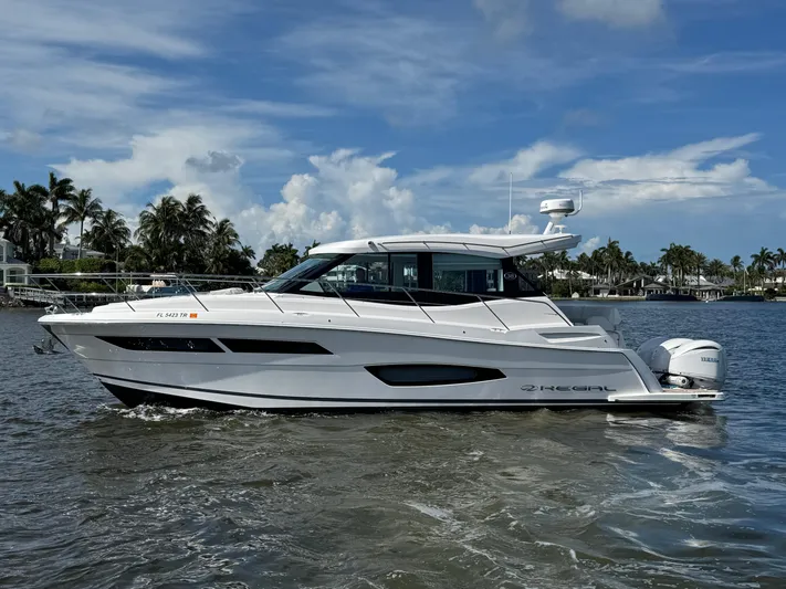 19th Hole Yacht Photos Pics 2024 Regal 38 XO yacht cruising on a sunny day with palm trees in the background.