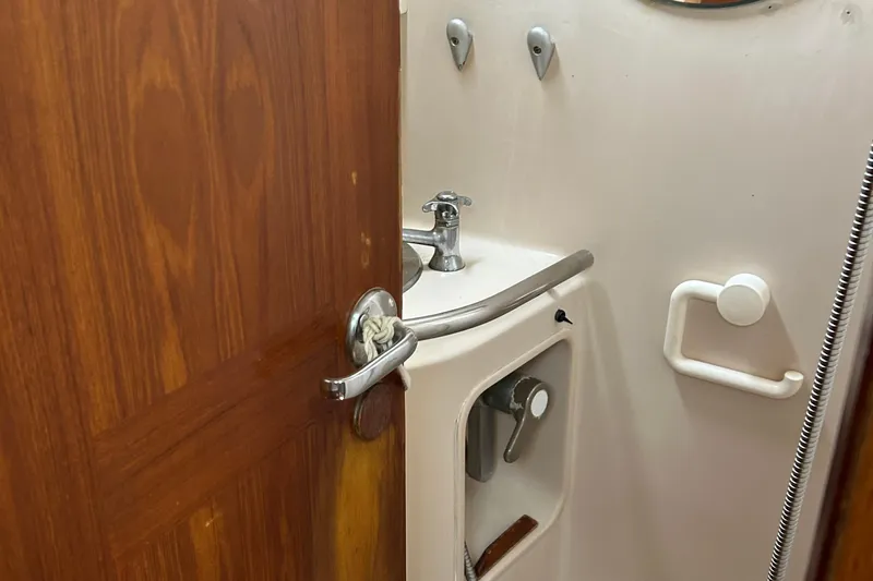 Zephyrus Yacht Photos Pics Bathroom interior of 1991 Beneteau 500 Oceanis yacht, featuring sink and wooden door.