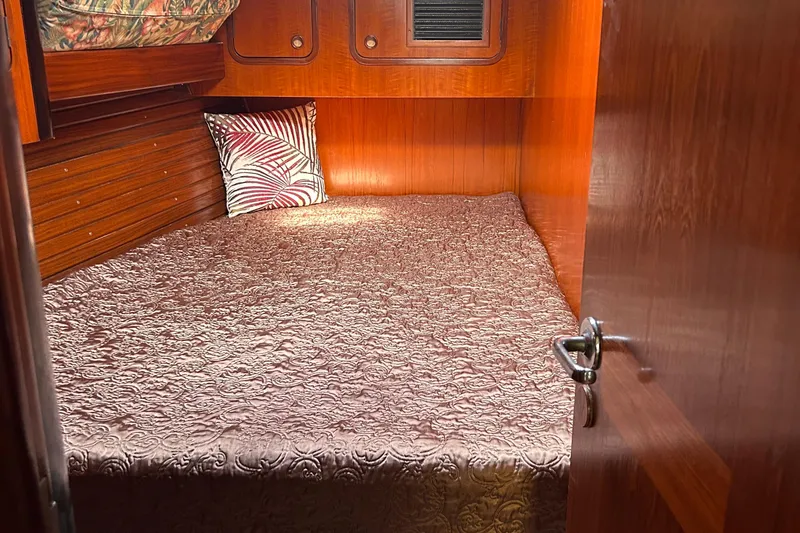 Zephyrus Yacht Photos Pics Cozy cabin interior of 1991 Beneteau 500 Oceanis with elegant bedding and wooden finish.