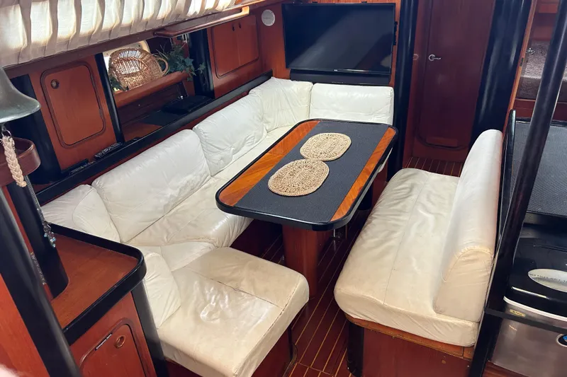 Zephyrus Yacht Photos Pics Interior of 1991 Beneteau 500 Oceanis yacht with white seating and wooden table.