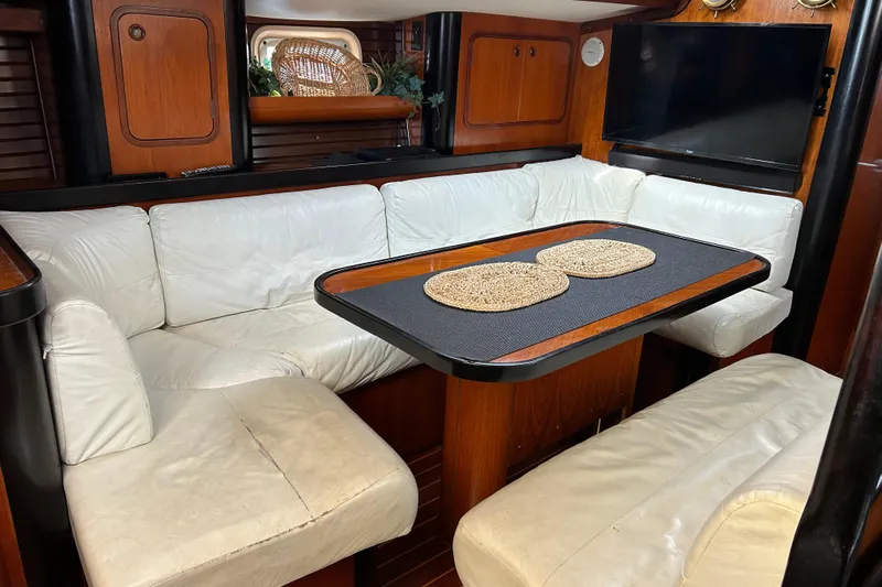Zephyrus Yacht Photos Pics Interior of 1991 Beneteau 500 Oceanis yacht with white leather seating and wooden table.